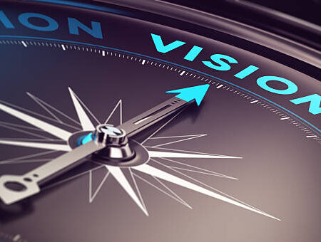 Compass with needle pointing the word vision with blur effect plus blue and black tones. Conceptual image for immustration of company or business anticipation or strategy